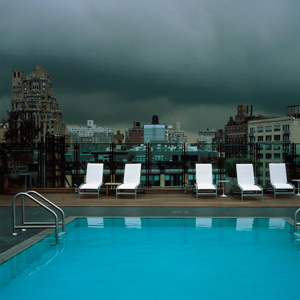From top; stormy clouds, white sun loungers, turquoise pool